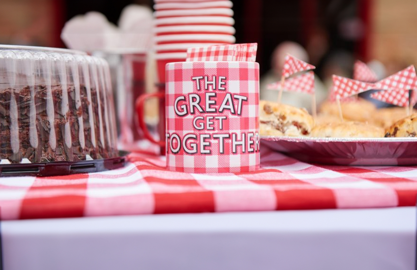 A photograph of a fancy table lay, with red and white themed decorations. A mug reads 'The Great Get Together'.