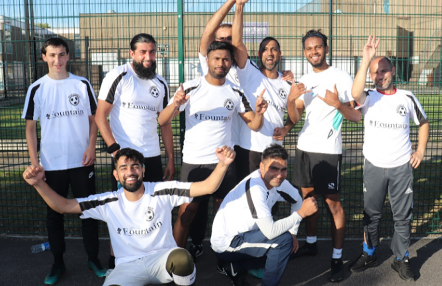 A group photo of young men celebrating in front of a football court